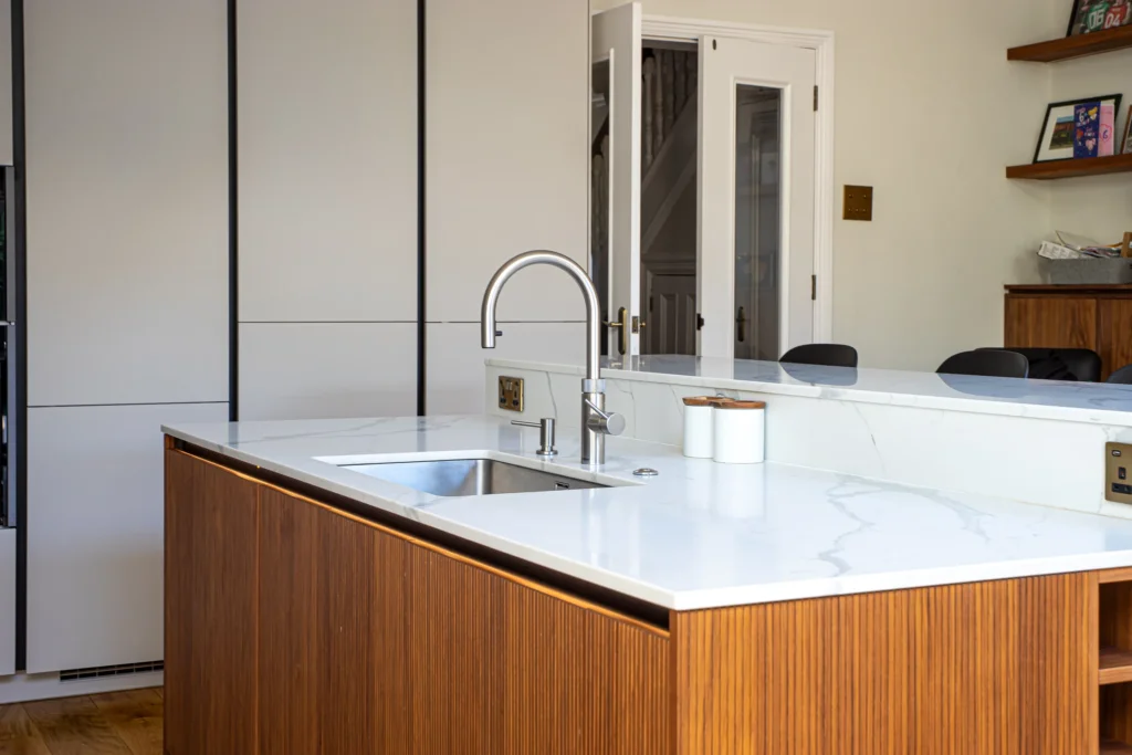 Cashmere matt handleless kitchen with fluted walnut island and marble worktops
