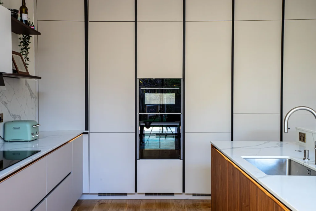 Signature cashmere matt kitchen with marble splashback and open walnut shelving
