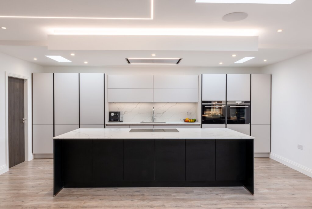 White matt handleless kitchen with graphite black island and marble worktops