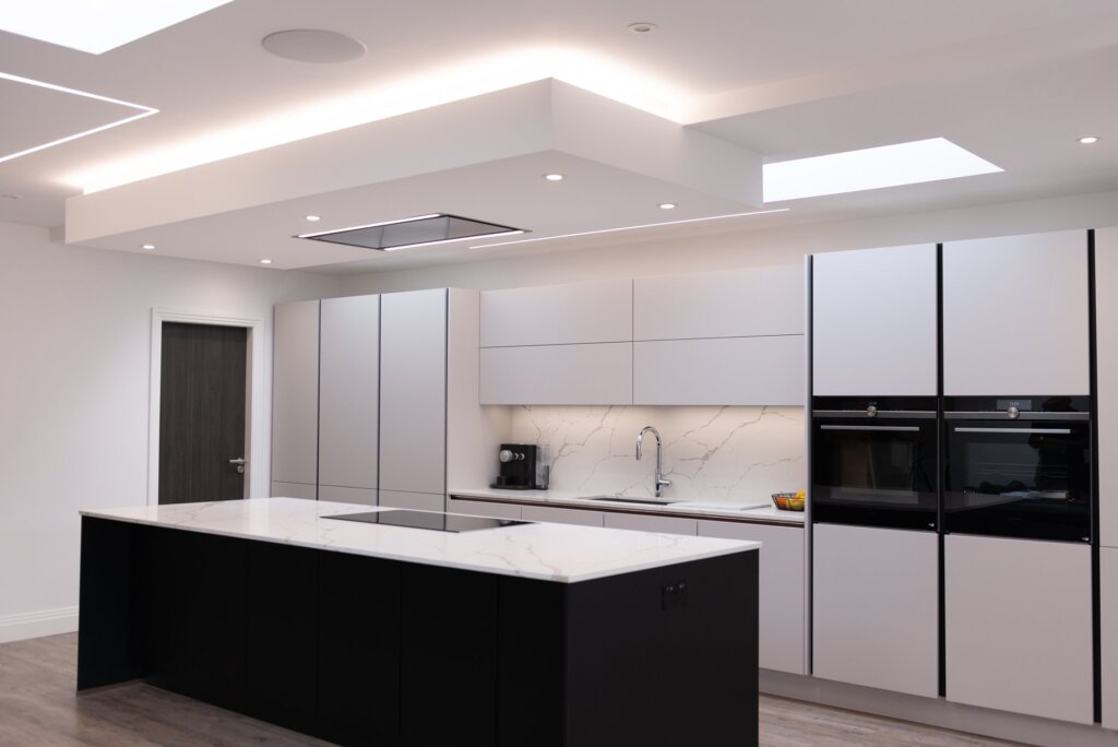 White matt handleless kitchen with full-height cabinetry and chrome tap