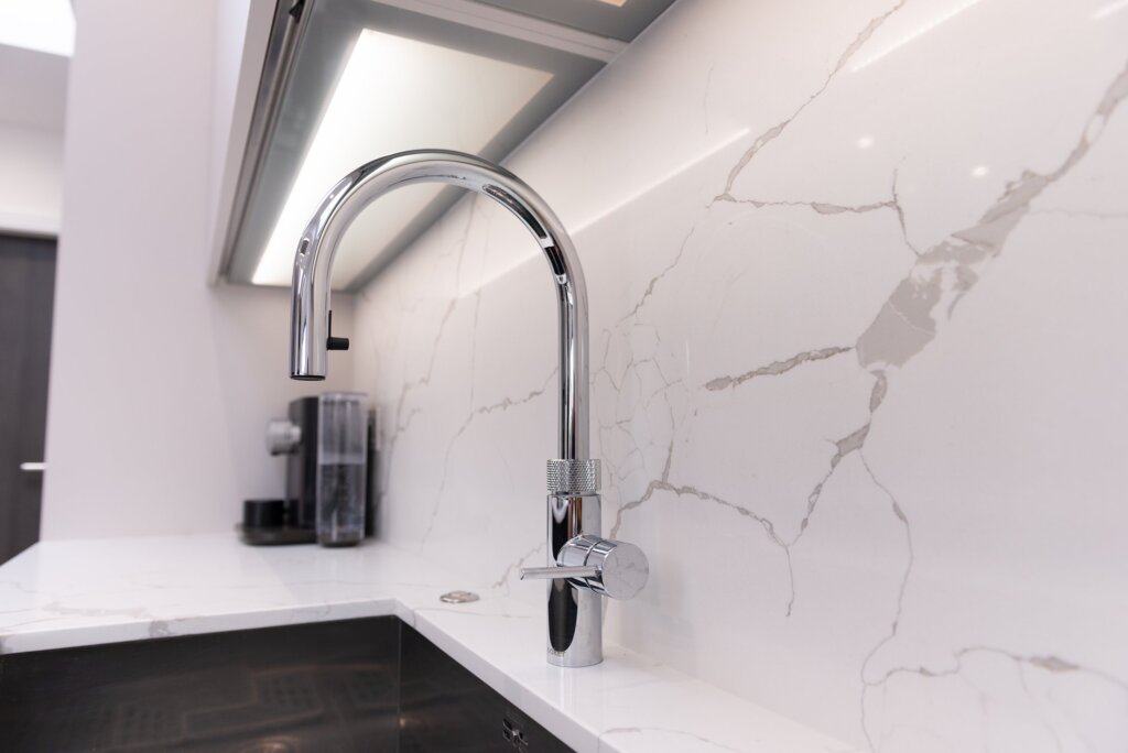 White matt handleless kitchen with graphite black island and marble worktops