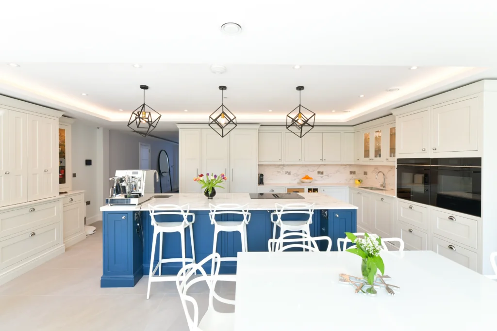 Large navy blue kitchen island with white marble quartz worktop and chrome cup handles in a bright room