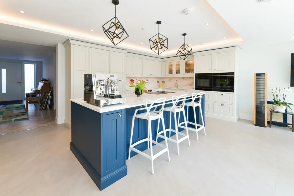 Pale cream shaker cabinets featuring glass display doors and integrated warm internal lighting over a sink