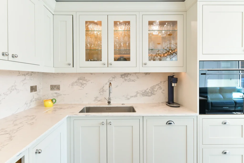 Large navy blue kitchen island with white marble quartz worktop and chrome cup handles in a bright room