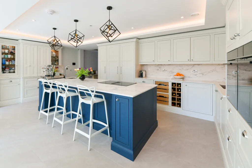Pale cream shaker cabinets featuring glass display doors and integrated warm internal lighting over a sink