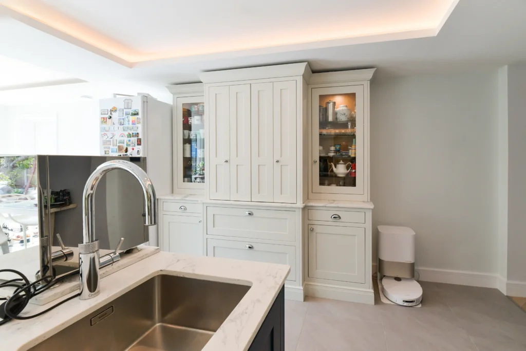 Large navy blue kitchen island with white marble quartz worktop and chrome cup handles in a bright room