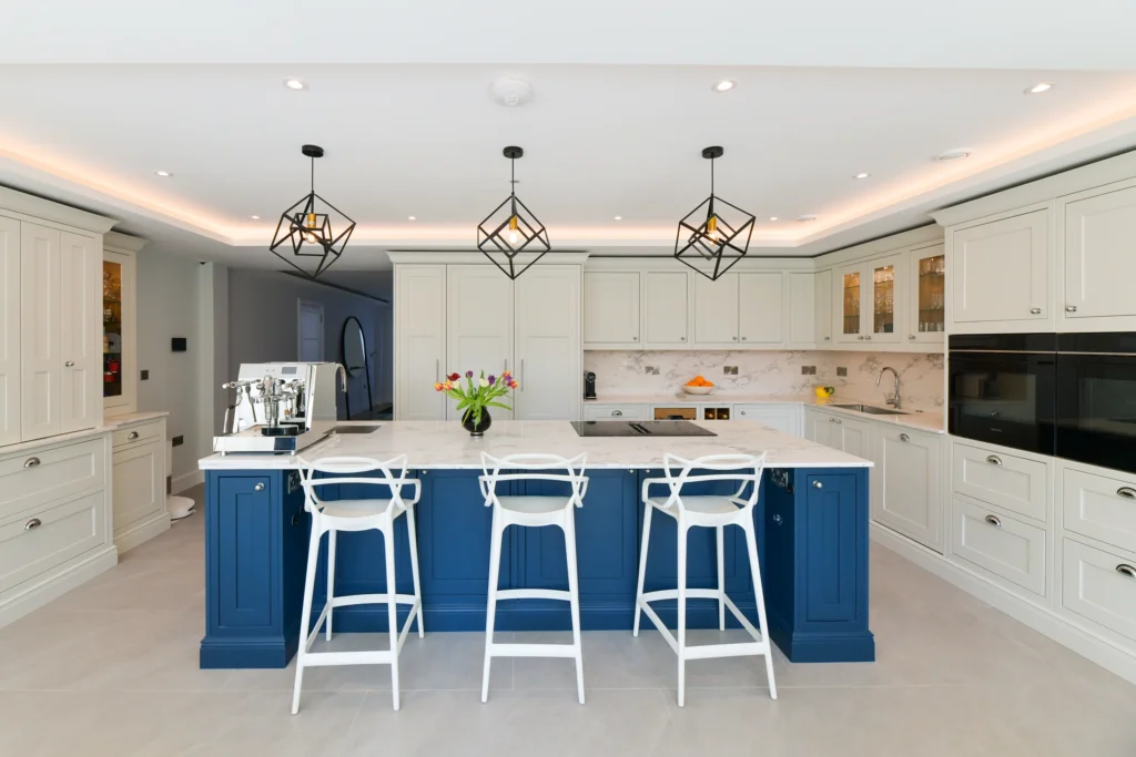 Pale cream shaker cabinets featuring glass display doors and integrated warm internal lighting over a sink