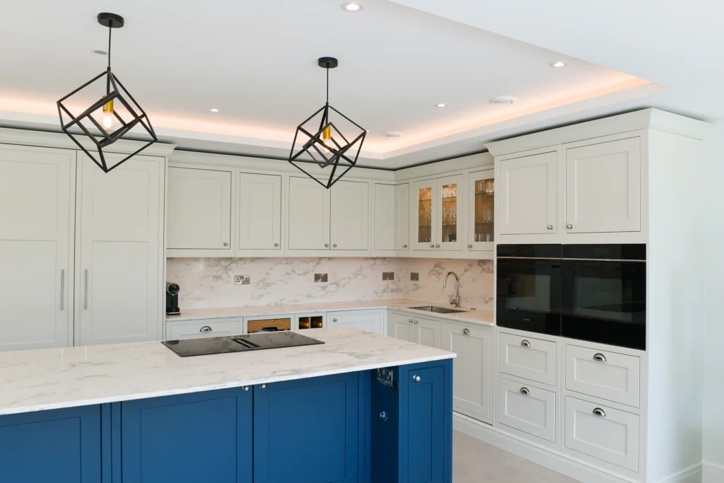 Pale cream shaker cabinets featuring glass display doors and integrated warm internal lighting over a sink
