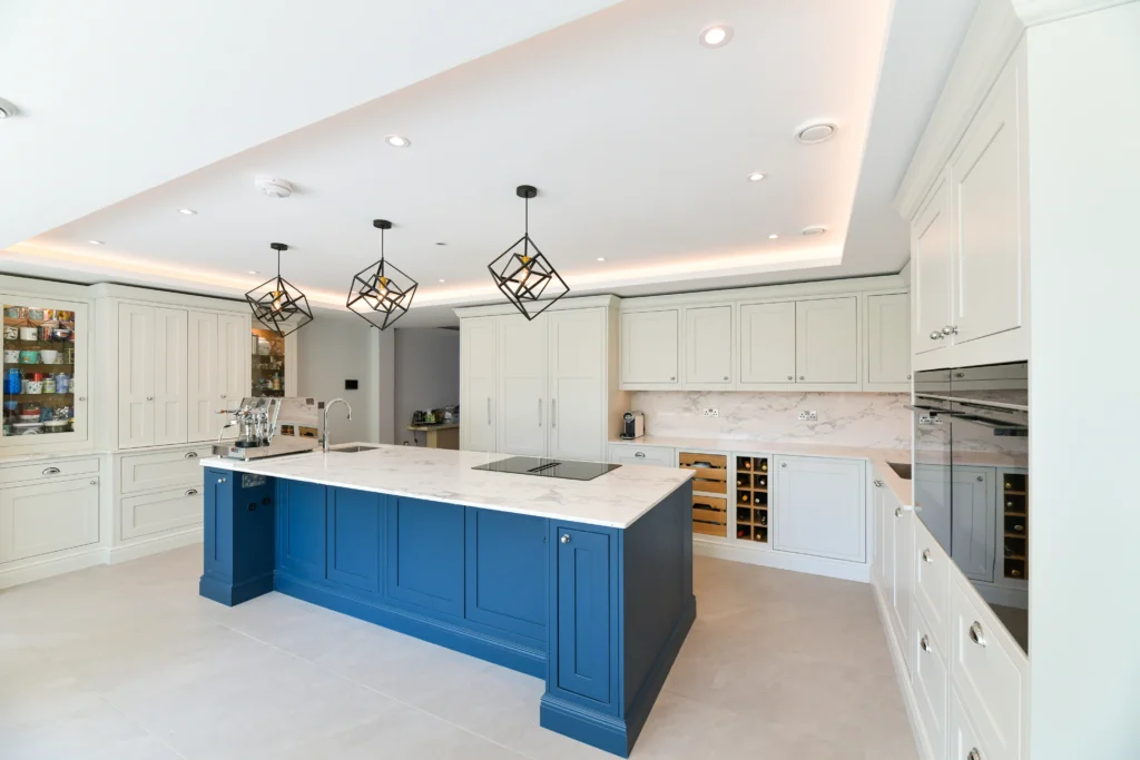 Pale cream shaker cabinets featuring glass display doors and integrated warm internal lighting over a sink