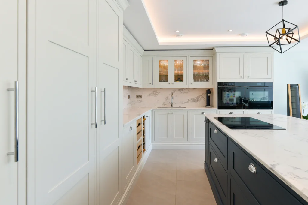 Large navy blue kitchen island with white marble quartz worktop and chrome cup handles in a bright room