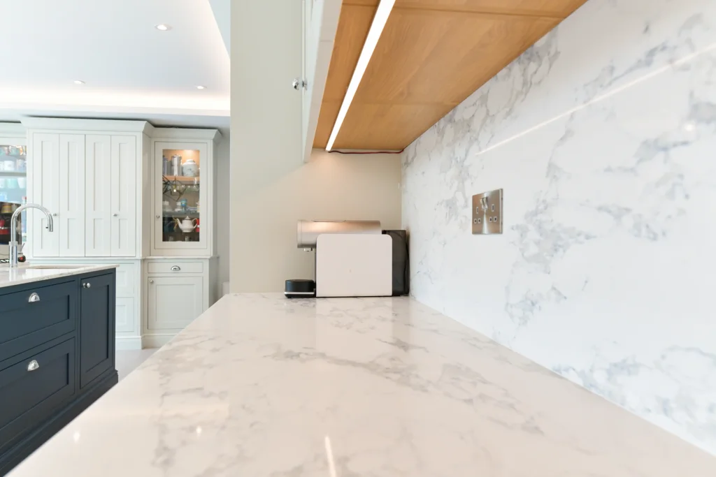 Large navy blue kitchen island with white marble quartz worktop and chrome cup handles in a bright room