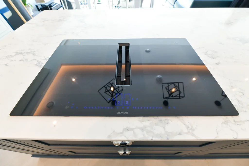 Large navy blue kitchen island with white marble quartz worktop and chrome cup handles in a bright room