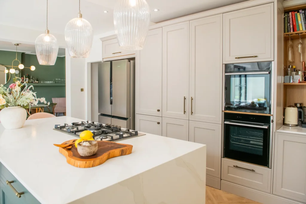Oak veneer handleless kitchen with backlit quartzite island and marble worktops