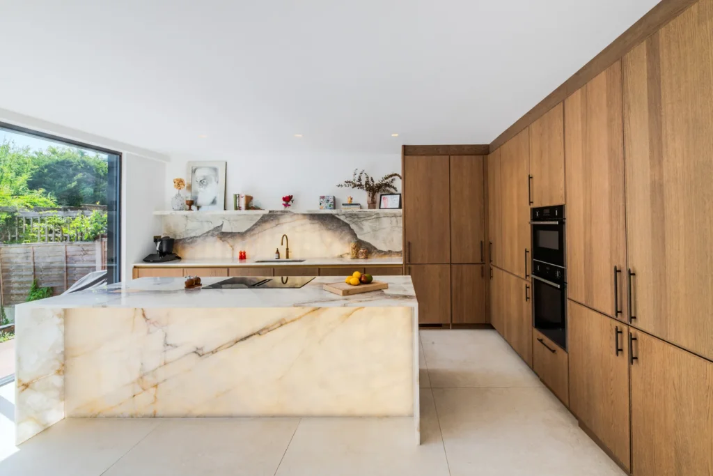 Oak veneer handleless kitchen with backlit quartzite island and marble worktops