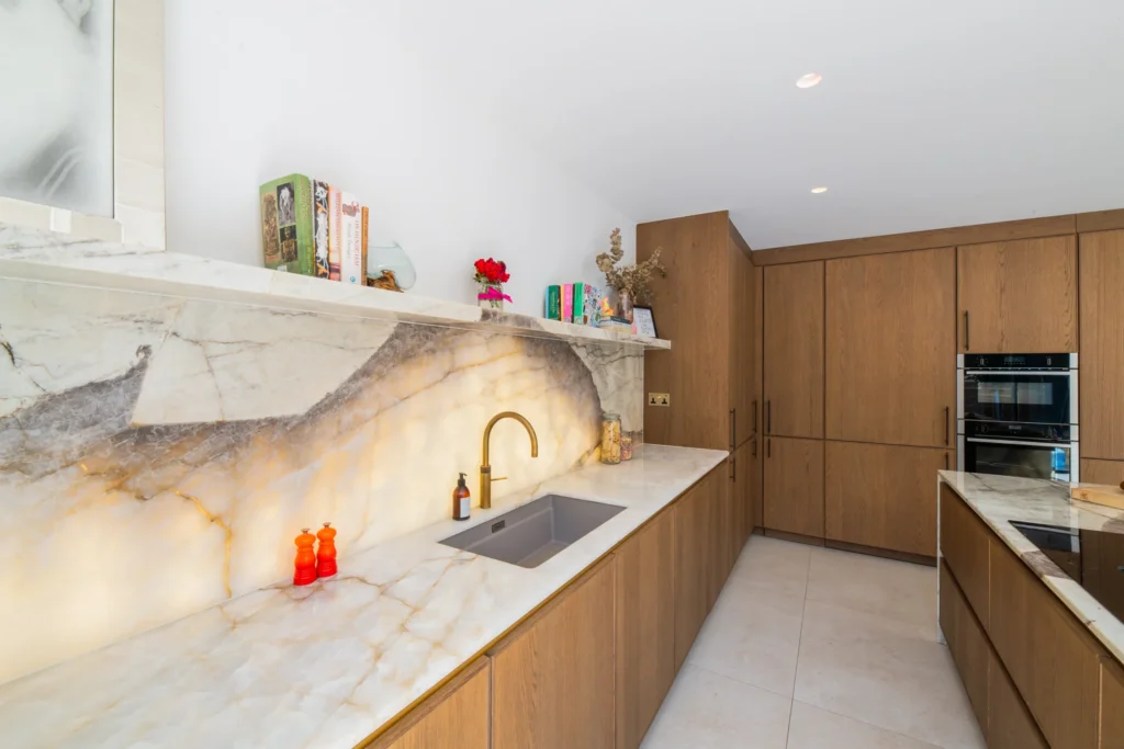 Oak veneer handleless kitchen with backlit quartzite island and marble worktops