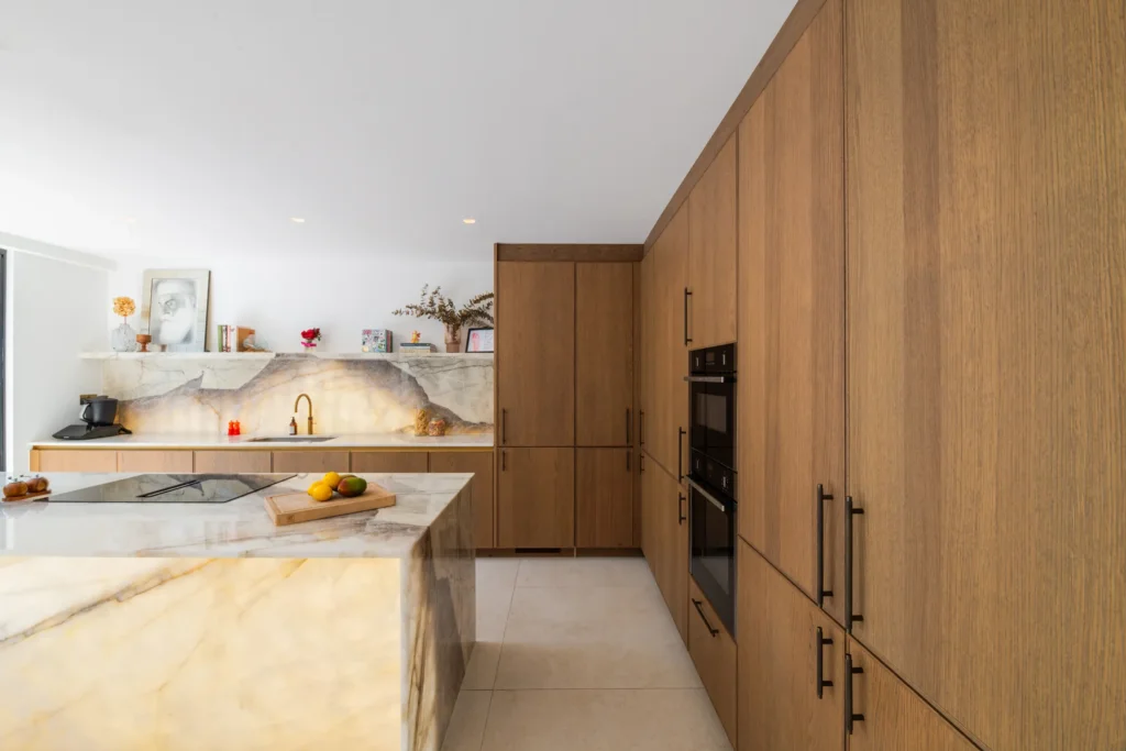 Oak veneer handleless kitchen with backlit quartzite island and marble worktops