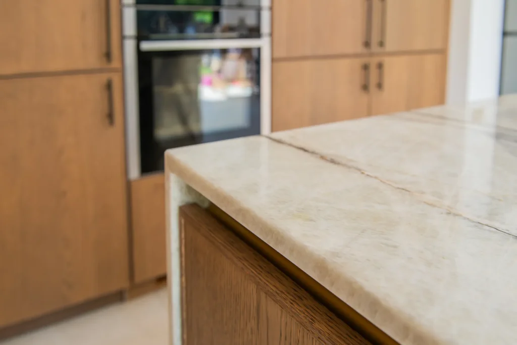 Oak veneer handleless kitchen with aged brass tap and quartzite splashback