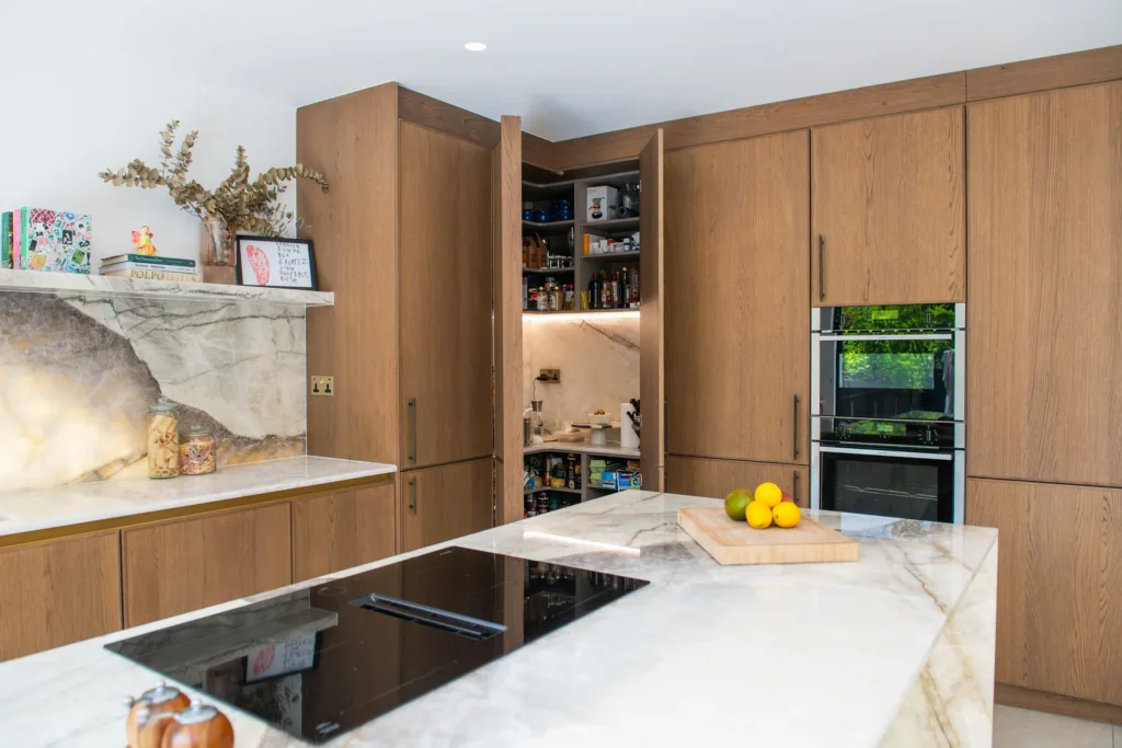 Oak veneer handleless kitchen with backlit quartzite island and marble worktops
