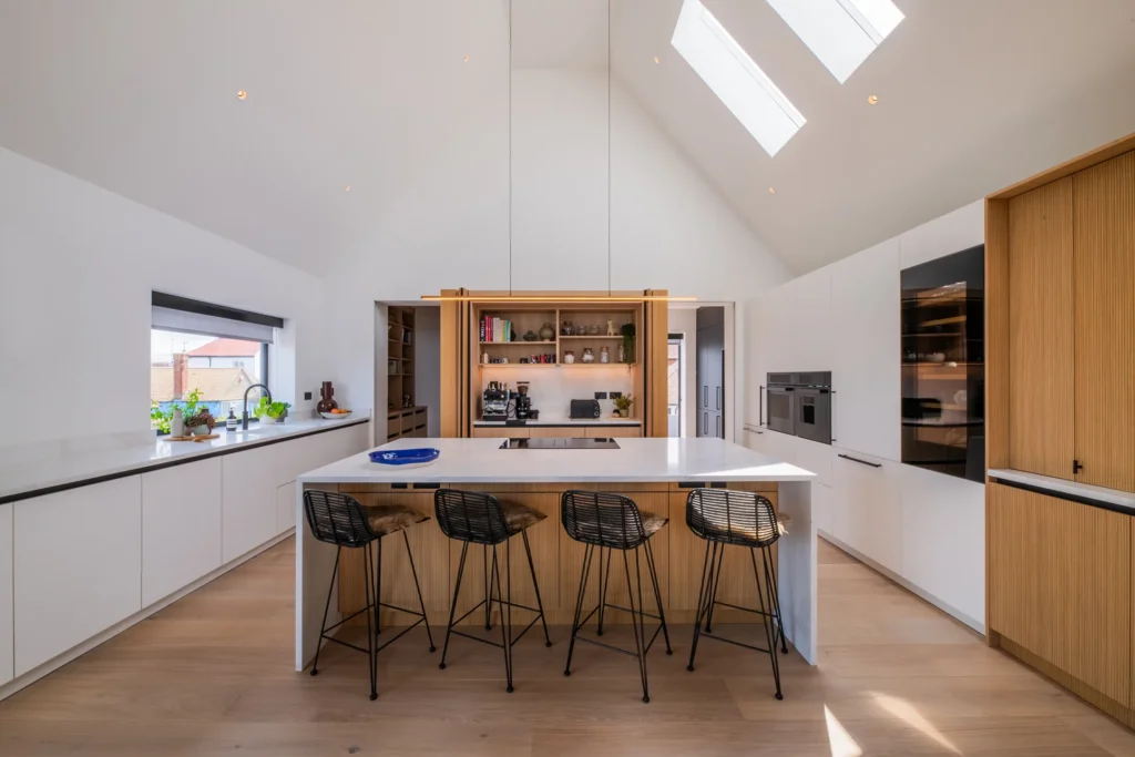 White handleless kitchen with vaulted ceiling, skylights and sea views