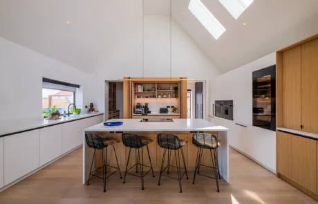 White handleless kitchen with vaulted ceiling, skylights and sea views