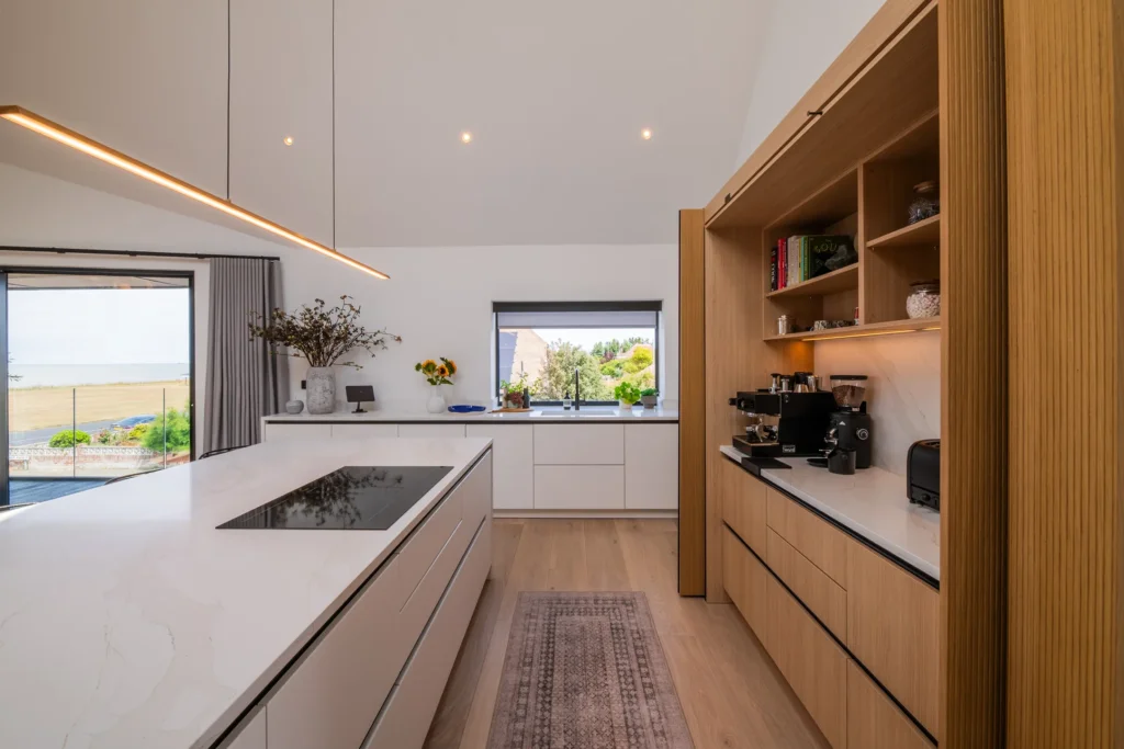 White handleless kitchen with oak cabinetry and marble-topped island