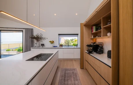 White handleless kitchen with oak cabinetry and marble-topped island