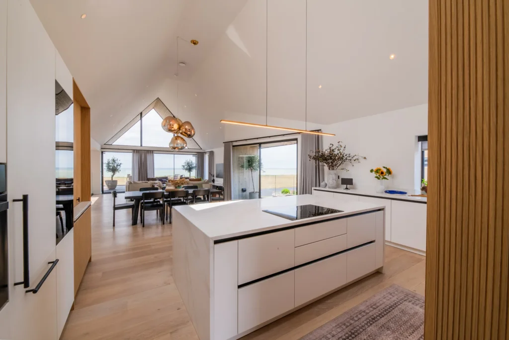 White handleless kitchen with vaulted ceiling, skylights and sea views