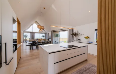 White handleless kitchen with vaulted ceiling, skylights and sea views