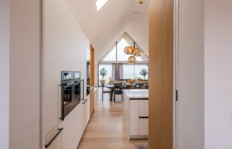 White handleless kitchen with oak drinks cabinet and integrated wine store