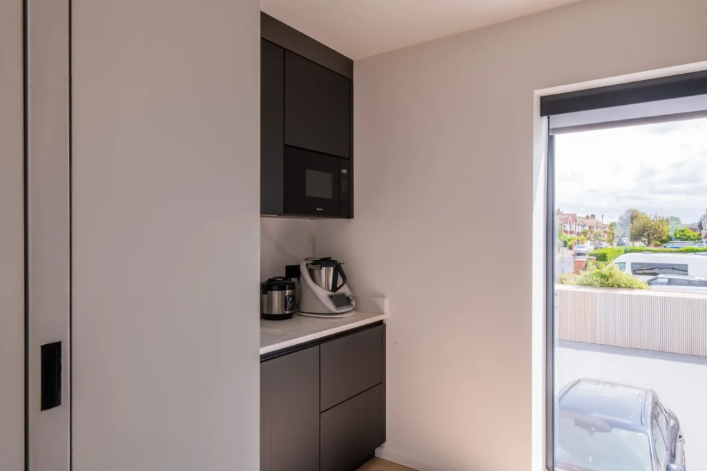 White handleless kitchen with oak island flowing into open-plan dining area