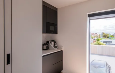 White handleless kitchen with oak island flowing into open-plan dining area