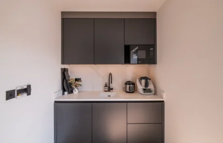 White handleless kitchen with black galley pantry and marble worktops
