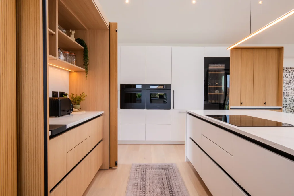 Signature white handleless kitchen with oak bi-fold pantry and coffee station