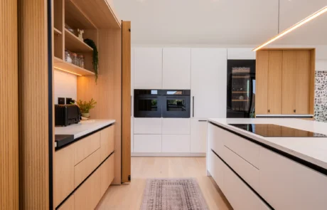 Signature white handleless kitchen with oak bi-fold pantry and coffee station
