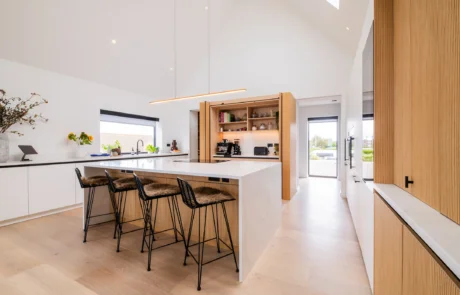 White handleless kitchen with oak cabinetry and marble-topped island