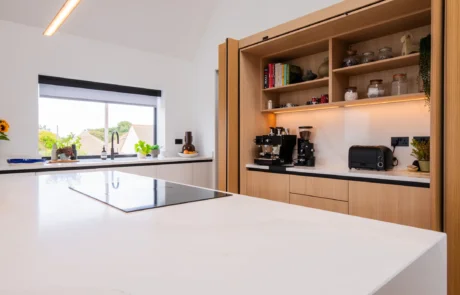 White handleless kitchen with vaulted ceiling, skylights and sea views