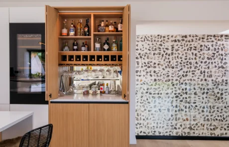 White handleless kitchen with oak drinks cabinet and integrated wine store