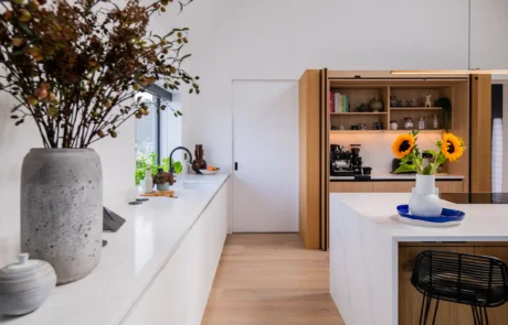 White handleless kitchen with black galley pantry and marble worktops