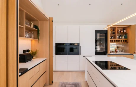 White handleless kitchen with oak drinks cabinet and integrated wine store