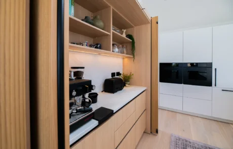 White handleless kitchen with vaulted ceiling, skylights and sea views